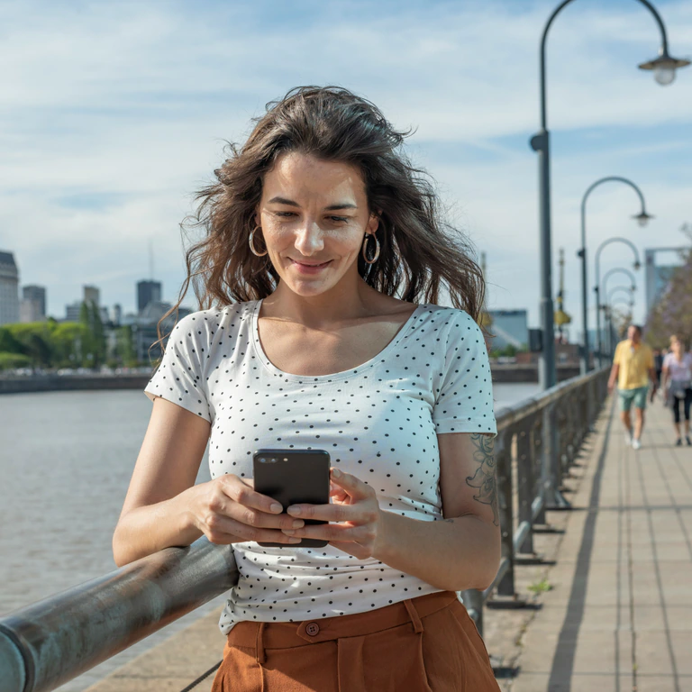 A smiling employee checking her CHIRAYOU results on her phone while out in the city.